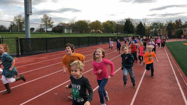 elementary aged students running on a track